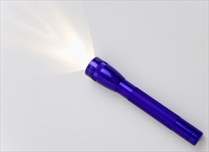 TOOLS, Household, Torch, Purple magilite torch turned on and casting a beam of light over a white