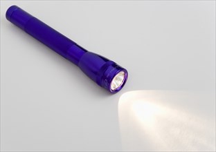 TOOLS, Household, Torch, Purple magilite torch turned on and casting a beam of light over a white