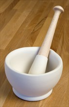 HOUSEHOLD, Kitchenware, Cooking, White ceramic pestle and mortar on a wooden kitchen surafce