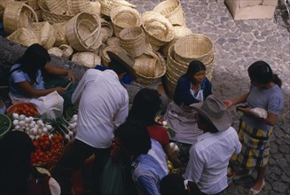MEXICO, Taxco, Looking down on customers at fruit and vegetable stall in market with piled baskets