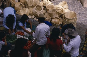 MEXICO, Taxco, Looking down on customers at fruit and vegetable stall in market with woven baskets