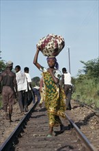 CONGO, Shaba Province, People, Young woman dressed in traditional local textiles carrying bundle on