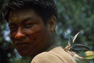 20088953 PERU  Rio Pachitea Portrait of young Campa tribesman with red and black painted face looking towards camera over his shoulder.
