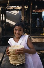 MEXICO, Oaxaca, Jucitan, Smiling young girl selling tortillas at market.