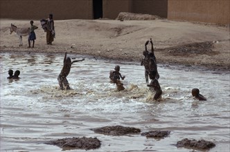 20088881 NIGER  Agadez Tuareg children playing in rain pool.