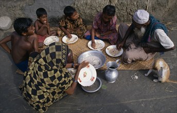 BANGLADESH, Khulna, Char Kukuri Mukuri, "Family having breakfast of rice, seated on mat laid on