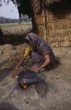 BANGLADESH, People, Woman cooking on small open fire with cooking pot held on raised clay surround.