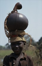 BURUNDI, Children, Portrait of Hutu child carrying water pot on head.
