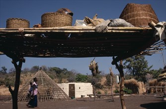 SENEGAL, Buildings, "Family enclosure with circular hut beside frame of roof, passing woman and