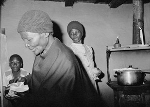 SOUTH AFRICA, KwaZulu Natal, Ekuvukeni, Gogo preparing for church watched by young boy  whilst