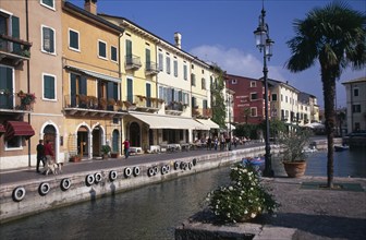 ITALY, Veneto, Lake Garda, Bardolino.  Harbour and line of waterside bars and cafes painted in