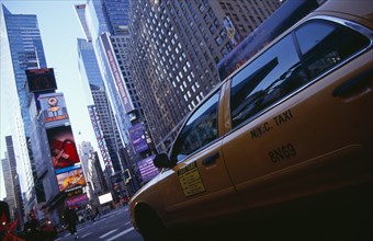 USA, New York, New York City, Times Square.  Yellow taxi cab on street with skyscraper buildings