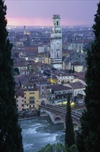 ITALY, Veneto, Verona, "Cityscape at sunset showing tiled rooftops, Duomo bell tower and bridge
