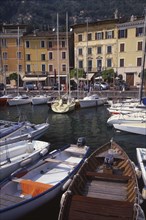 ITALY, Lombardy, Lake Garda, Gargnano.  Waterside buildings with boats moored in harbour in the