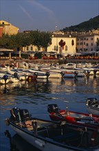 ITALY, Veneto, Lake Garda , Garda.  Harbour view with cafe tables set out on quayside overlooked by
