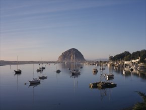 USA, California, Morro Bay, Harbour with moored yachts and Morro Rock seen across water