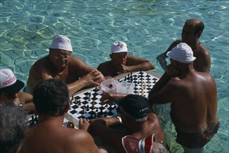 HUNGARY, Budapest, Szecheny Baths. A group of men playing a game of Chess in the thermal water