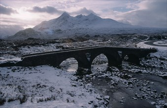 SCOTLAND, Isle of Skye, Sligachan and the Cuillin Mountains in winter snow.  Narrow bridge over