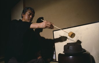 JAPAN, Honshu, Kyoto, "Grand Tea Master Sen Soshitsu pouring water from kettle or kama heated on