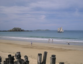 FRANCE, Brittany, St Malo, Le Sillon Beach and Fort National. People walking along golden sand with