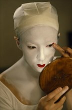JAPAN, Arts, Performance, Kabuki actor Tamasaburo looking in hand mirror to apply make-up for role
