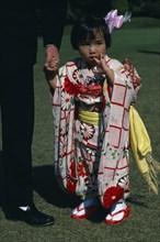 JAPAN, Honshu, Tokyo, Little girl holding the hand of a part seen guest at Shinto wedding ceremony