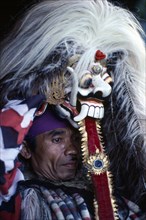 INDONESIA, Bali, Religion, Portrait of village man with head dress topped with mask depicting the