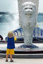 SINGAPORE, MARINA BAY, "A YOUNG BOY LOOKS ON AT A MINI VERSION OF THE MERLION STATUE. The Merlion