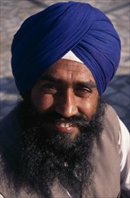 INDIA, Delhi, Head and shoulders portrait of Sikh man wearing blue turban.
