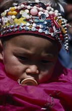 CHINA, Xinjiang Province, Altai Region, Portrait of Kazakh baby wearing hat covered with silver