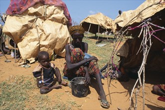 SOMALIA, Kisamio, Woman and child sitting outside makeshift shelter in camp for displaced people.