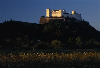 AUSTRIA, Salzburg, Hohensalzburg fortress situated on densely wooded hillside with meadows below.