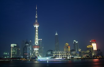 CHINA, Shanghai, Pudong at night with illuminated skyscrapers and buildings including the Oriental