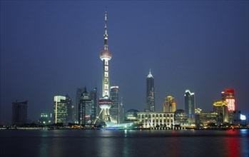 CHINA, Shanghai, Pudong at night with illuminated skyscrapers and buildings including the Oriental