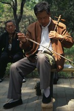 CHINA, Beijing, "Musician in Tian Tian Park playing an Erhu, traditional Chinese violin."