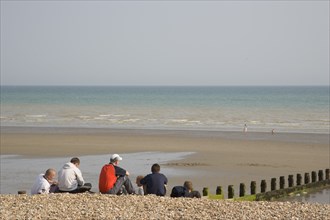 ENGLAND, West Sussex, Bognor Regis, A group of teenage boys sitting on shingle and sand beach