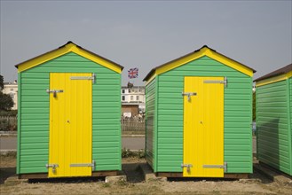 ENGLAND, West Sussex, Littlehampton, Green and yellow beach huts next to promenade with a Union