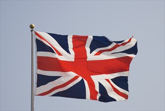 ENGLAND, West Sussex, Littlehampton, British Union Jack flag flying in the wind against a blue sky
