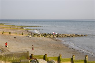 ENGLAND, West Sussex, Selsey, Children playing with bucket and spade on sandy beach next to sea