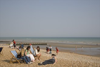 ENGLAND, West Sussex, Bognor Regis, A group of girls sitting on deck chairs on shingle beach with