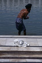 INDIA, Uttar Pradesh, Delhi, Sikh man washing himself whilst wearing kachs.