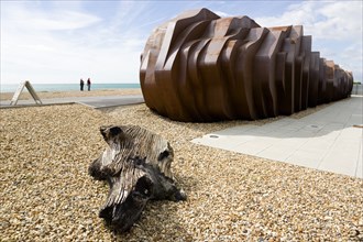 ENGLAND, West Sussex, Littlehampton, Two people standing on the beach looking at the rusted metal