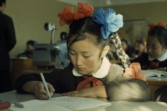 MONGOLIA, Education, Altai SecondarySchool  11 year old girl writing at desk with her hair plaited