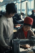 MONGOLIA, Work, Woman working at sewing machine in Ulan Bator tannery  leather factory with a young