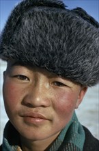 MONGOLIA, Children, Altai provincial capital. Portrait of young boy with typical fur hat with ear