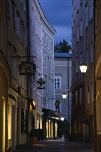 AUSTRIA, Salzburg, "Narrow street of Judengasse at night lined by tall, grey, pink and cream