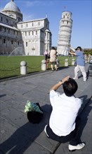 ITALY, Tuscany, Pisa, Asian male tourist taking a photograph of another Asian man pretending to