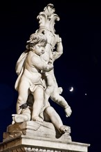 ITALY, Tuscany, Pisa, An illuminated statue in The Piazza del Duomo of cherubs holding a shield