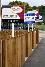 ENGLAND, West Sussex, Washington, To Let signs on wooden fencing outside a newly built housing