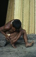 COLOMBIA, North West Amazon, Tukano Indigenous People, Barasana man removing palm spine from foot